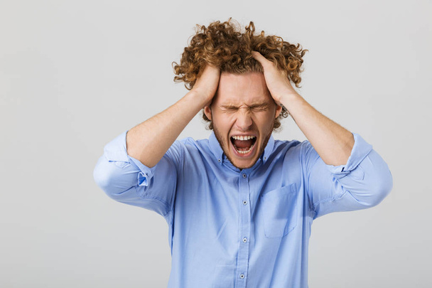 Portrait of a mad young man with curly hair isolated over white background, shouting - Foto, immagini