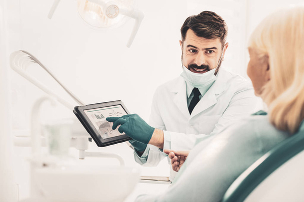 Dentist holding tablet and talking with patient - Foto, Imagen