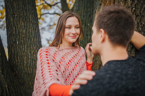 Młoda kobieta spojrzenie na człowieka i uśmiech. Ona jest w miłości. Kobieta dotyka go. Opiera się on na drewno. - Zdjęcie, obraz