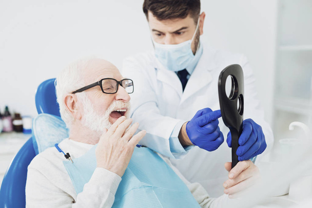 Pleasant senior man estimating dentists work - Foto, Bild