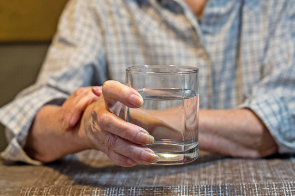 mains de vieilles femmes tenant un verre d'eau - Photo, image