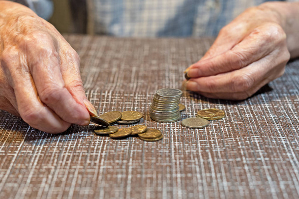 Ręce starszej kobiety i monety dla zbawienia. koncepcja oszczędzania pieniędzy. Zbliżenie. - Zdjęcie, obraz