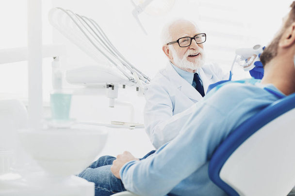 Experienced male dentist curing patient - Photo, image