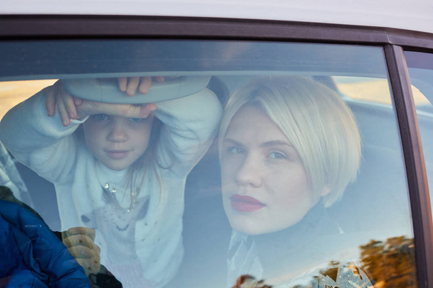Concepto familiar. Retrato de madre e hija a través del cristal de un coche
 - Foto, Imagen