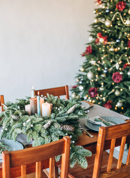 festive decorations and table setting inside the room with the Christmas tree and garlands - Foto, afbeelding