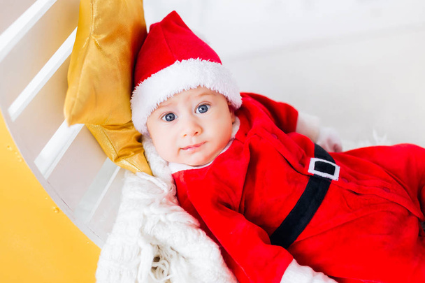 Close-up of a little boy in a Santa Claus costume that looks in the camera lens - Photo, image