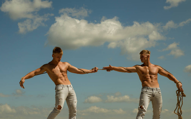 Opposites in sport. Men shows off their strength against competitors. Athletic twins on opposite sides. Twins competitors with muscular bodies. Strong men pull rope with muscular hand strength - Foto, imagen