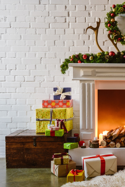 christmas decorations with gift boxes near warm fireplace in living room - Fotó, kép