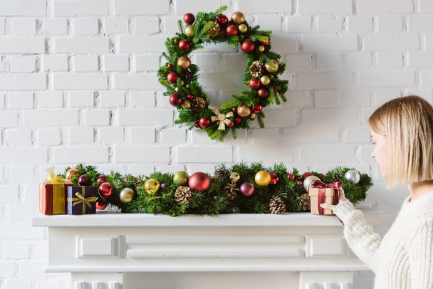 christmas wreath and decorations over fireplace mantel with white brick wall - Photo, Image