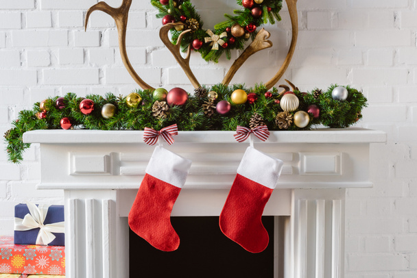 christmas wreath with decorations, stockings and deer horns over fireplace mantel - Фото, изображение