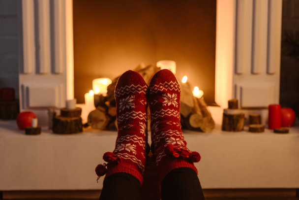 vista cortada de mulher em meias festivas de inverno com lareira no fundo
 - Foto, Imagem