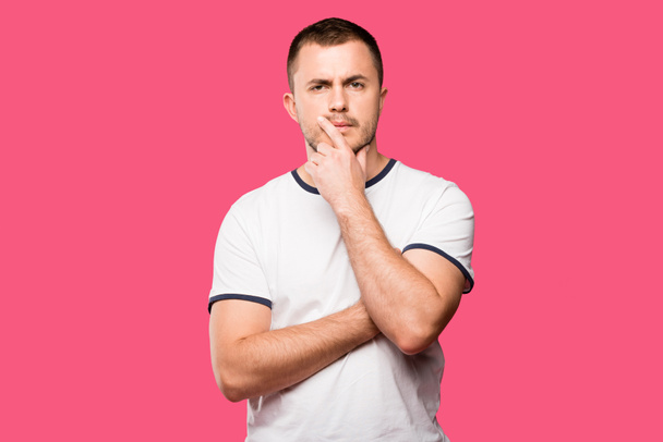 thoughtful young man with finger on chin isolated on pink - Foto, afbeelding