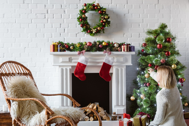  giovane donna decorazione albero di Natale con le bagattelle in soggiorno
  - Foto, immagini