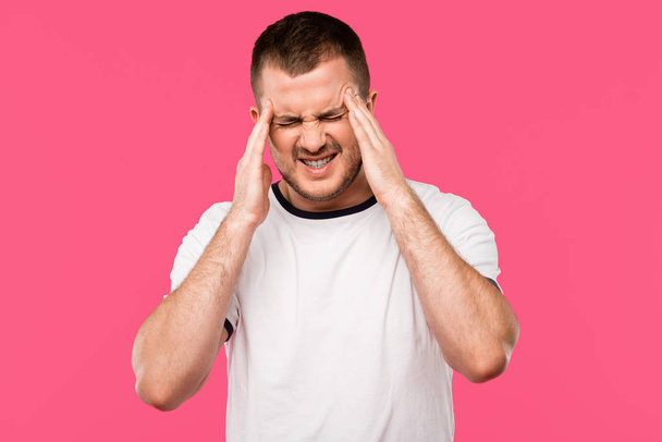 Nuori mies, jolla on voimakas päänsärky eristetty vaaleanpunainen
 - Valokuva, kuva