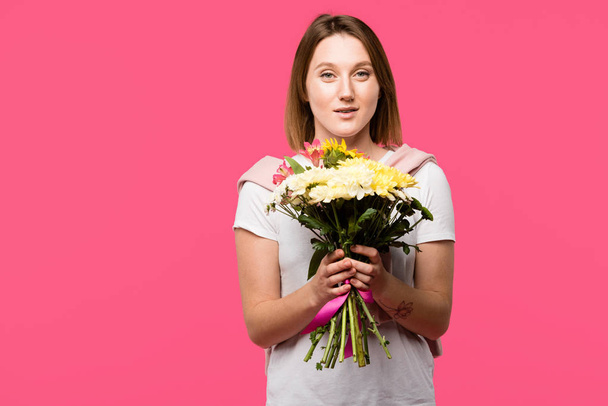 happy young woman holding colorful bouquet from various flowers isolated on pink - Zdjęcie, obraz