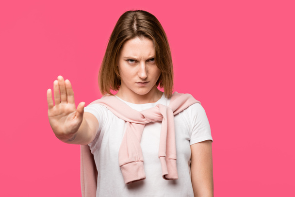 агресивна молода жінка, що показує стоп- жест ізольовано на рожевому
 - Фото, зображення