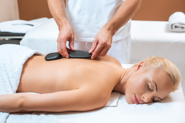Woman enjoying hot stone massage in spa salon  - Photo, Image