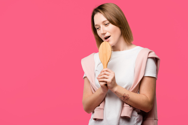 beautiful girl holding hairbrush and singing isolated on pink  - Photo, Image