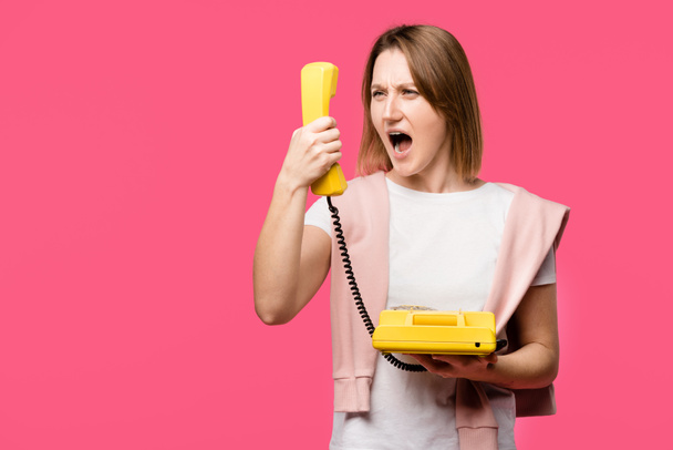 сердитая молодая женщина кричит на телефон изолирован на розовый
 - Фото, изображение