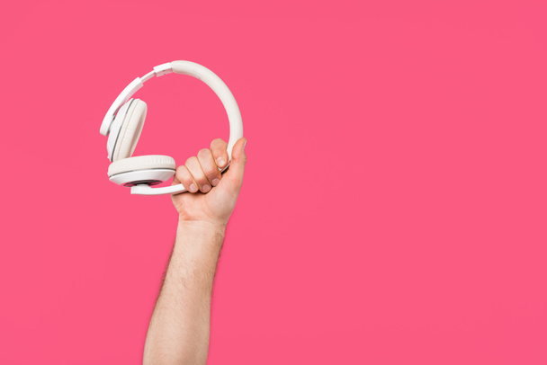 cropped shot of man holding white headphones isolated on pink - Fotoğraf, Görsel