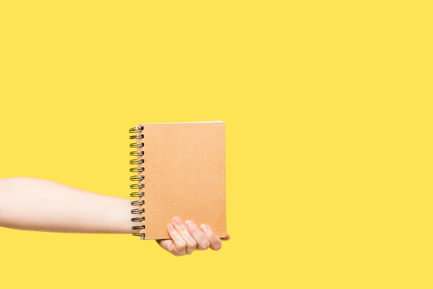 foto recortada de la persona que sostiene el cuaderno aislado en amarillo
 - Foto, Imagen