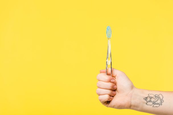 oříznuté shot osoby držící zubní kartáček izolované na žluté  - Fotografie, Obrázek
