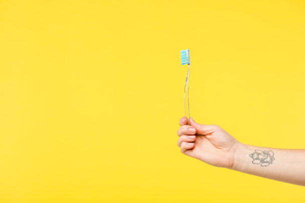 cropped shot of person holding toothbrush isolated on yellow  - Fotó, kép