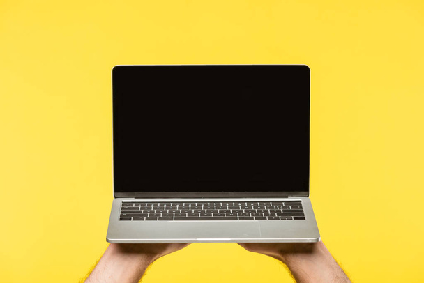 recortado de la persona que sostiene el ordenador portátil con pantalla en blanco aislado en amarillo
  - Foto, Imagen