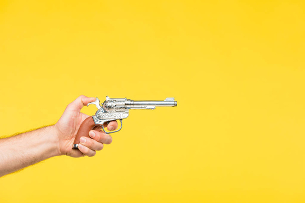 cropped shot of person holding revolver isolated on yellow - Photo, Image
