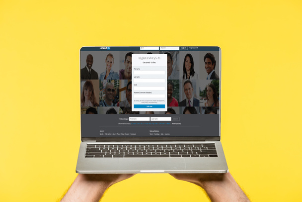 cropped shot of person holding laptop with linkedin website on screen isolated on yellow - Fotó, kép
