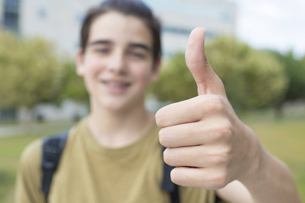молодой студент-подросток с большим пальцем вверх в знак успеха и одобрения
 - Фото, изображение