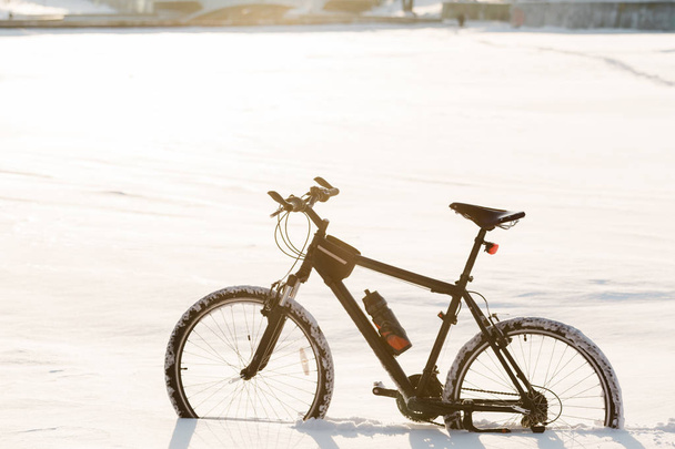 Ciclismo de invierno. Una bicicleta negra en la nieve. Deporte en cualquier época del año concepto
. - Foto, imagen