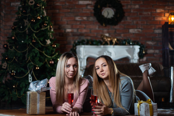 pretty young girlfriends or sisters celebrate Christmas together at home lying on the floor - Zdjęcie, obraz