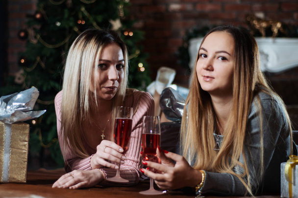 pretty young girlfriends or sisters celebrate Christmas together at home lying on the floor - Zdjęcie, obraz