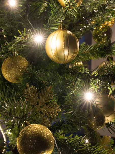 Detailní pohled na vánoční stromek se zlatými ornamenty a jasných zářivých světel v noci - Fotografie, Obrázek