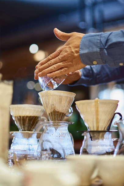 Barista pouring water into cup of ground coffee on scale - 写真・画像