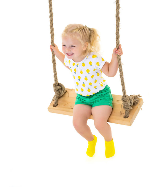 Little girl swinging on a swing - Фото, изображение