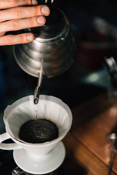 Immagine ravvicinata verticale di barista che versa acqua bollente dal bollitore alla caffettiera Drip in ceramica
.  - Foto, immagini