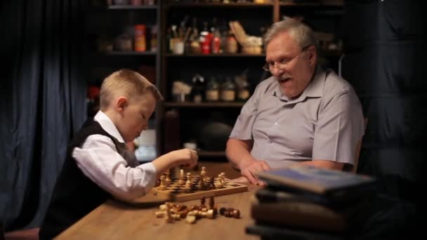 Happy grandfather plays chess with small grandson. - Footage, Video
