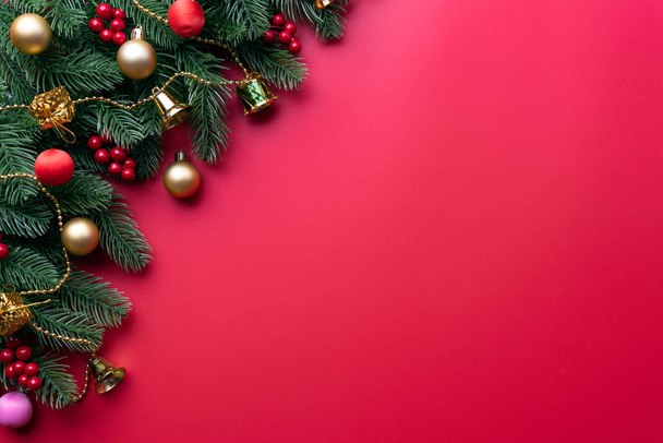 Concetto di sfondo natalizio. Vista dall'alto della confezione regalo di Natale palline rosse con rami di abete rosso, pigne, bacche rosse e campana su sfondo rosso
. - Foto, immagini