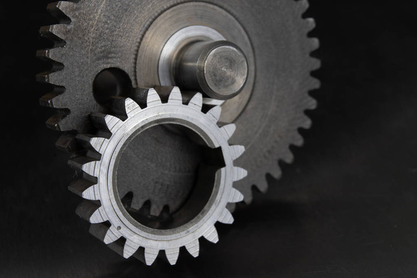 Gears on a metal workshop table. Spare parts for industrial machines. Dark background. - Foto, Imagem