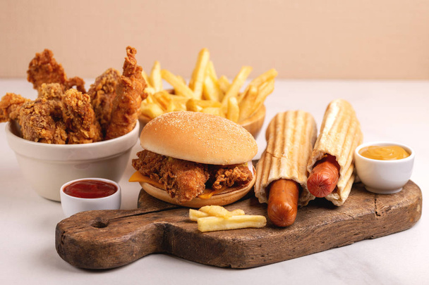 Delicious but unhealthy food with ketchup and mustard on vintage cutting board. Fast carbohydrates, junk and fast food. Light marble background. - Foto, imagen