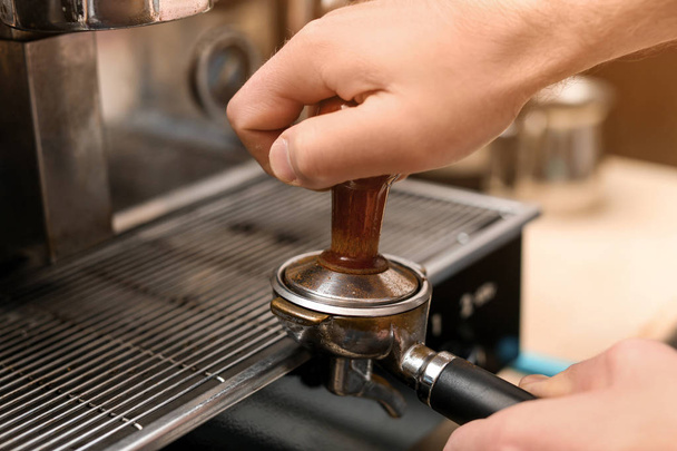 Male barista making espresso using professional coffee machine, closeup - Foto, Bild