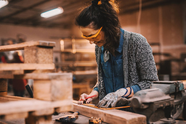 Carpintero femenino trabajando en taller. Mujer haciendo el concepto de trabajo masculino
. - Foto, Imagen