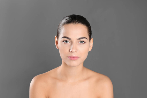Portrait of beautiful young woman on grey background. Lips contouring, skin care and cosmetic surgery concept - Fotó, kép