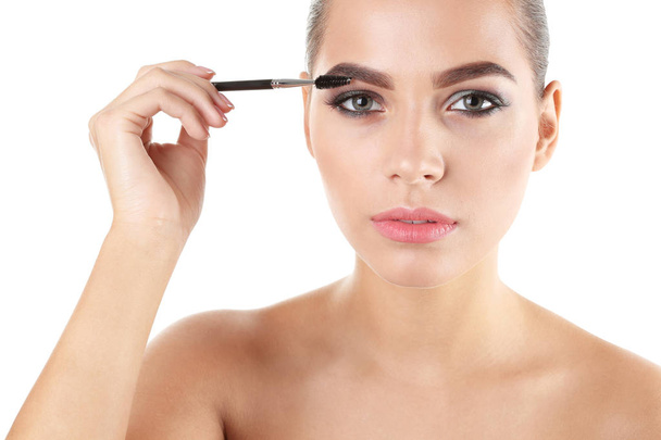Portrait of beautiful woman applying stylish makeup with brush on white background - Foto, imagen