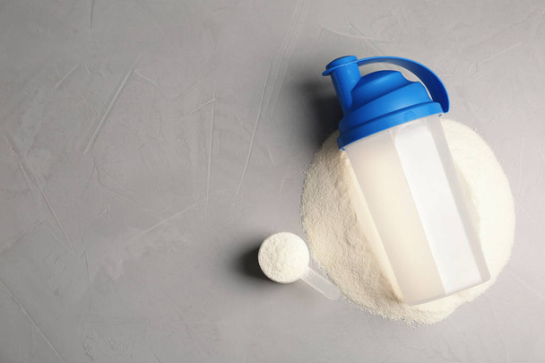 Bottle, protein powder and space for text on grey background, top view. Preparing shake - Фото, зображення