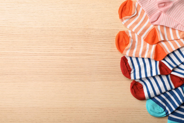 Cute child socks on wooden background, top view. Space for text - Фото, зображення