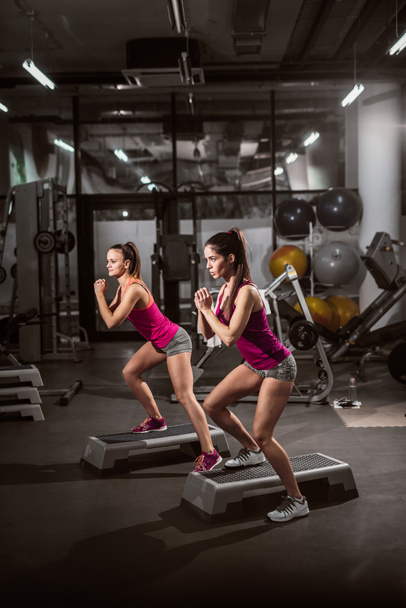 deux jeunes femmes sportives faisant des exercices sur les steppers dans la salle de gym
 - Photo, image