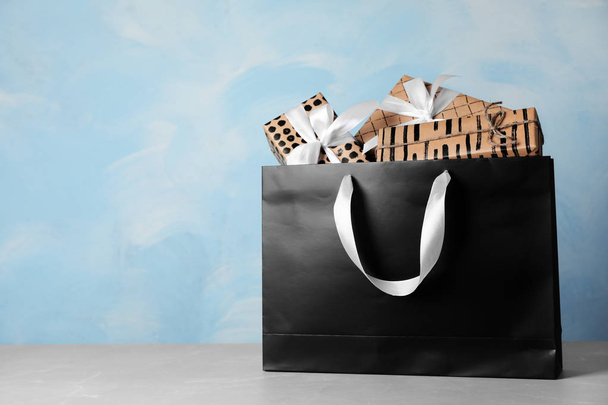 Paper shopping bag with handles full of gift boxes on table. Mock up for design - Foto, Imagem